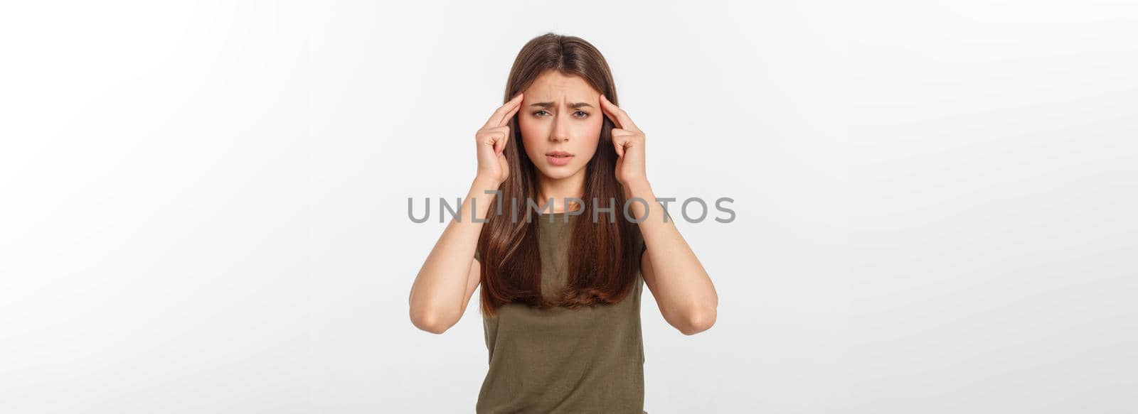 A young attractive woman suffering from illness or headache holding her head. Isolated on white.
