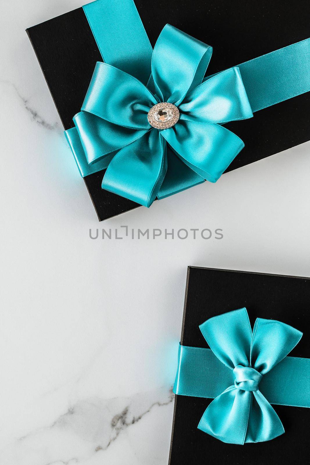 Luxury holiday gifts with emerald silk ribbon and bow on marble background by Anneleven