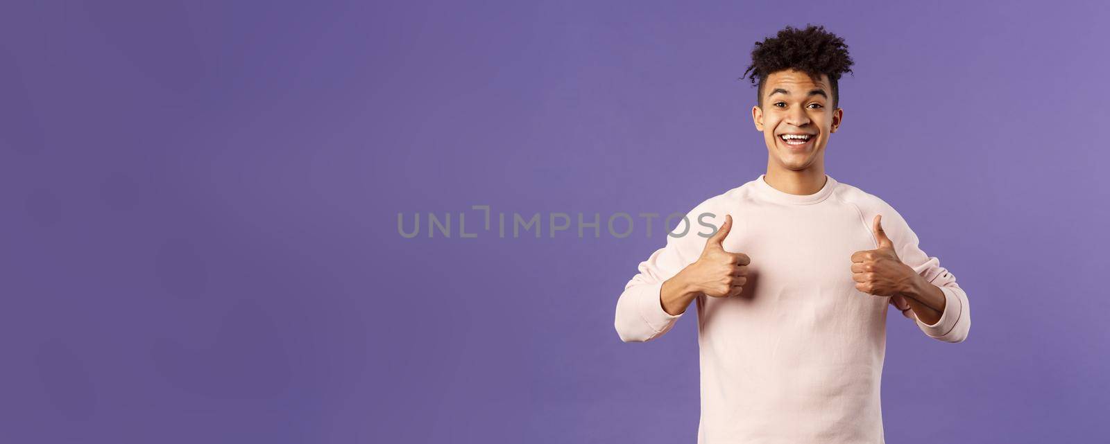 Portrait of upbeat, happy smiling man left pleased after using company service, studying at online language school, show thumbs-up and look camera, recommending, stand purple background.