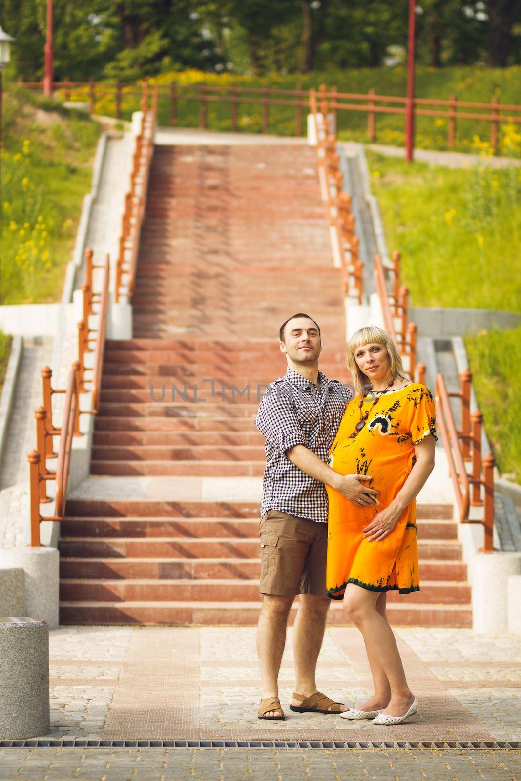 Man and his pregnant wife standing on staircase