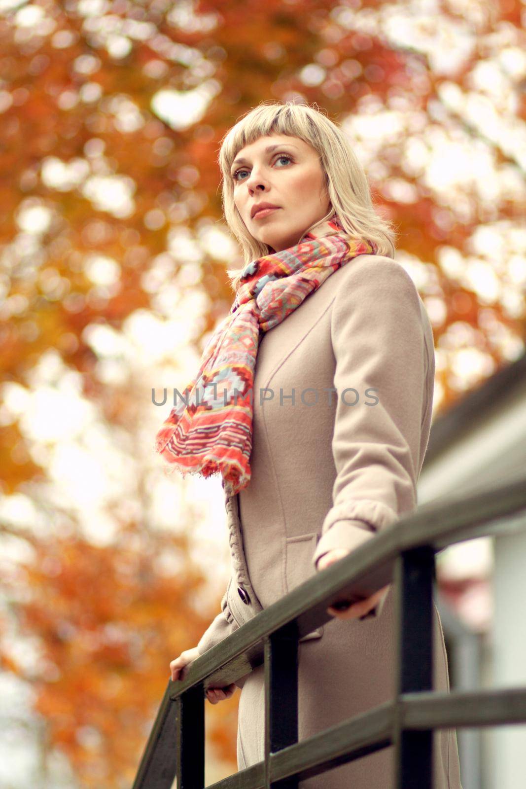 Autumn fashion girl wearing light trench coat in sun flare foliage