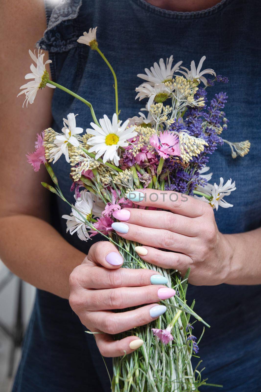 a young woman with a beautiful summer manicure holds a bouquet of wild flowers by KaterinaDalemans
