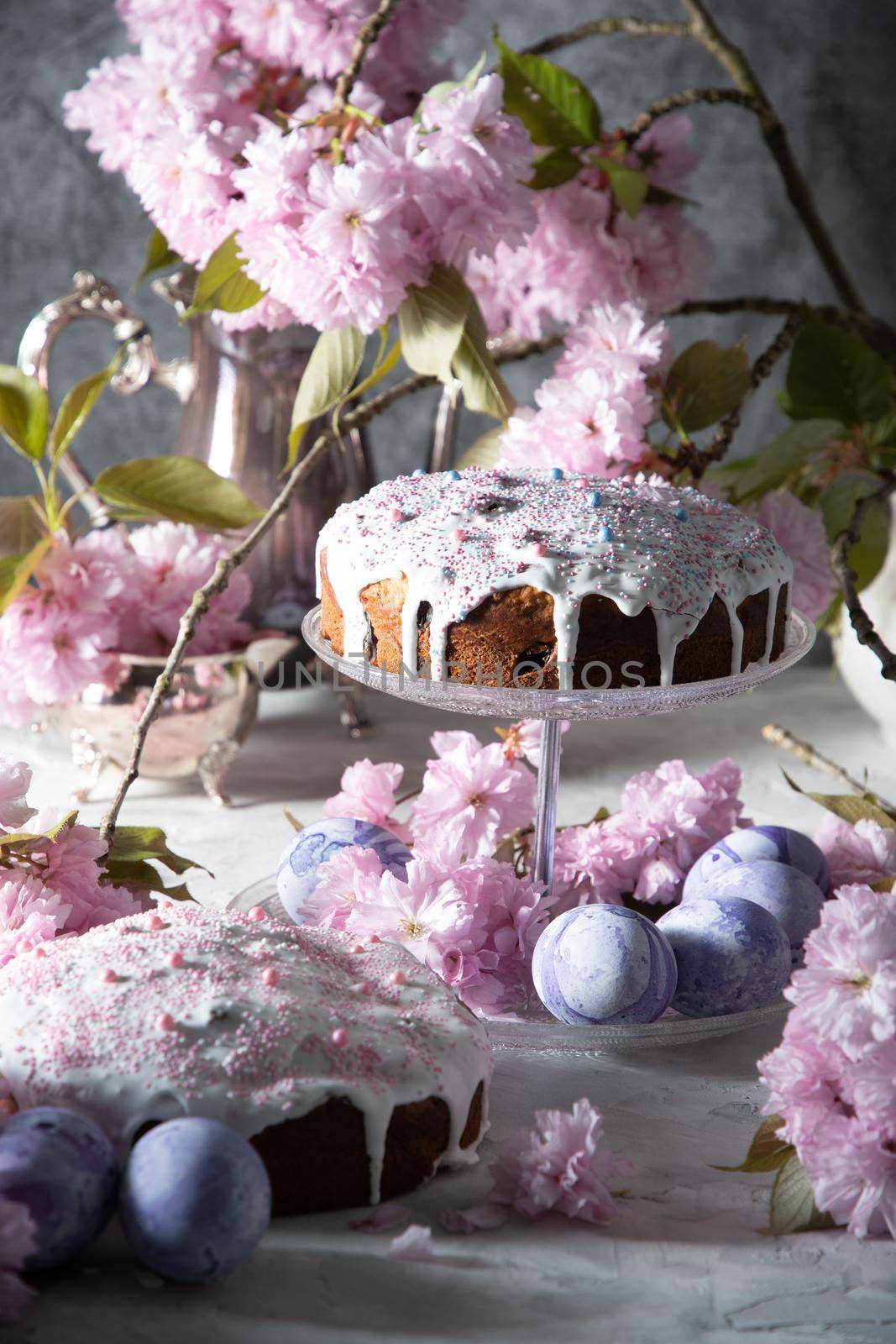 beautiful Easter cake on the table, and colored eggs, homemade cakes, still life with a silver teapot on a background of pink sakura. High quality photo