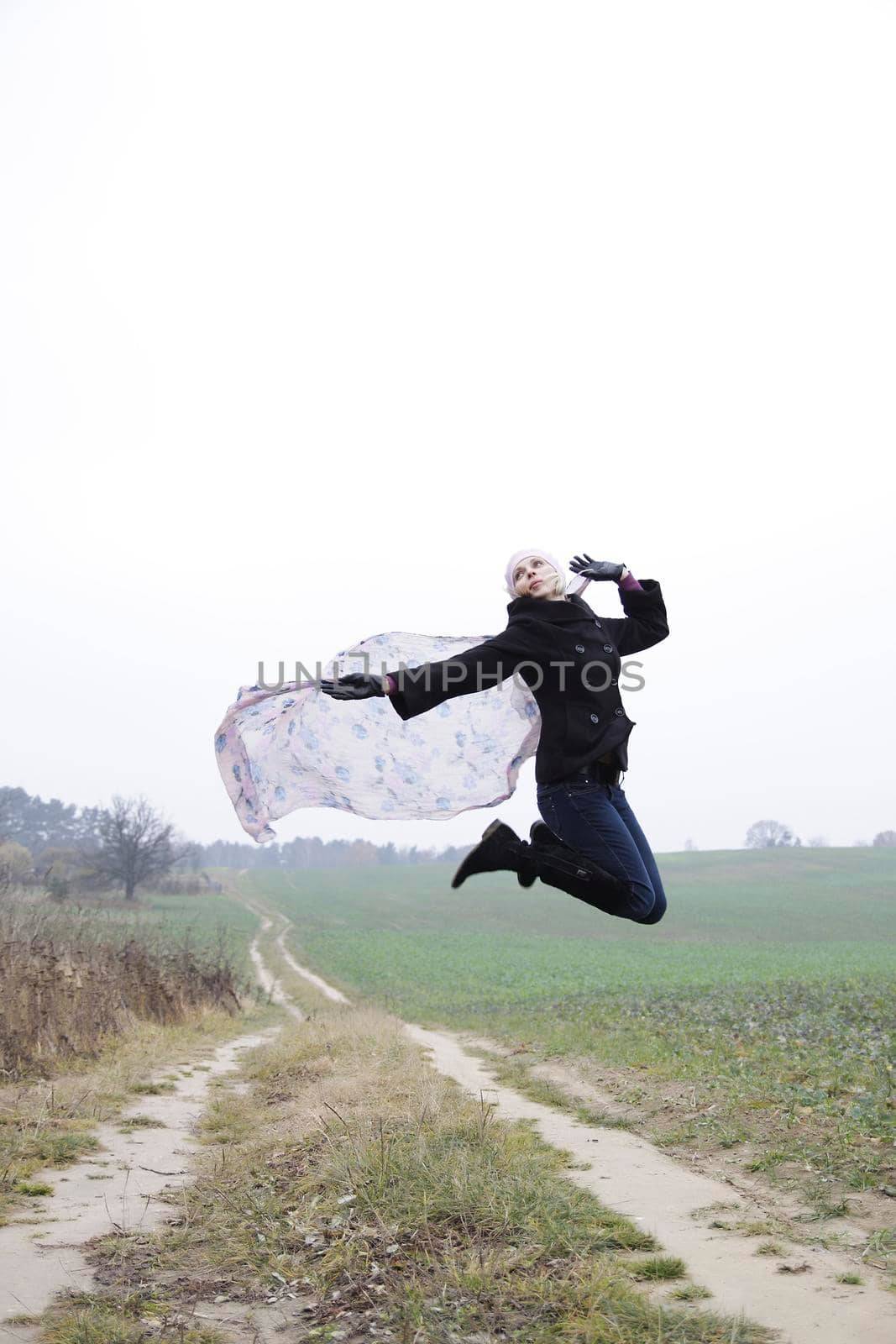 Portrait of jumping young blonde woman on field