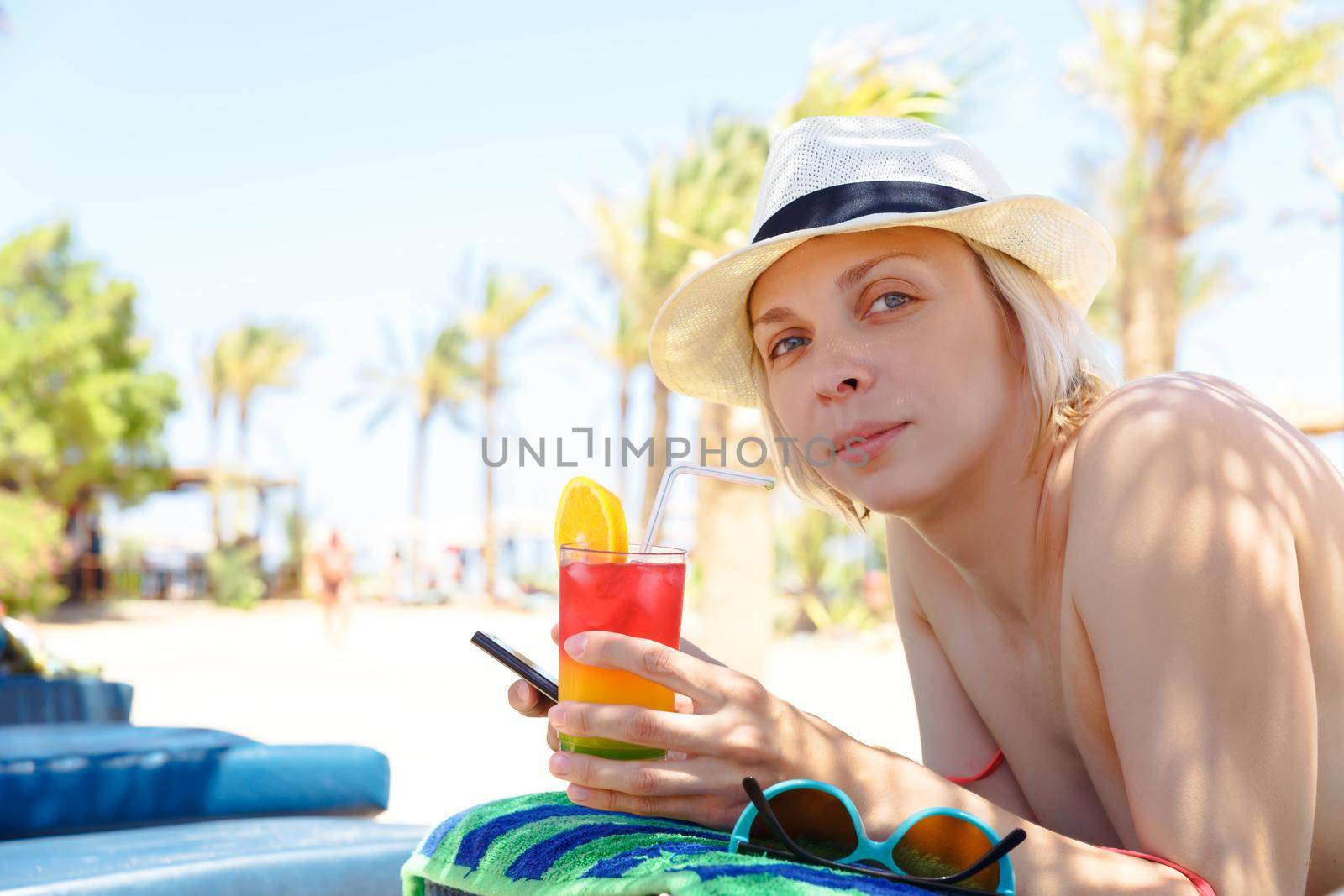 Woman in bikini drinking alcohol cocktail through a straw.