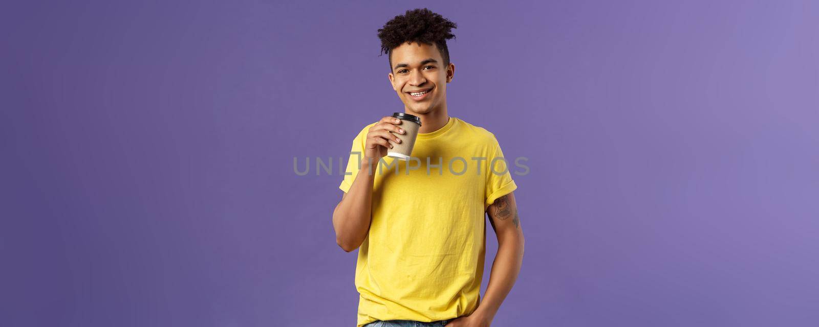 Portrait of good-looking young male student with dreads, tattoos, casually drinking coffee from take-away cup, visit favorite cafe, smiling cheerful, enjoying perfect warm sunny day by Benzoix