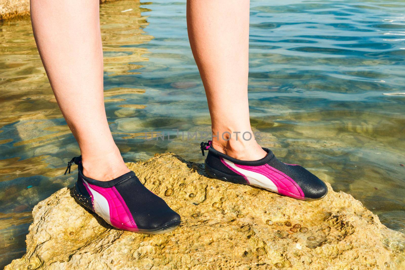 Swimming neoprene shoes in water on beach. 