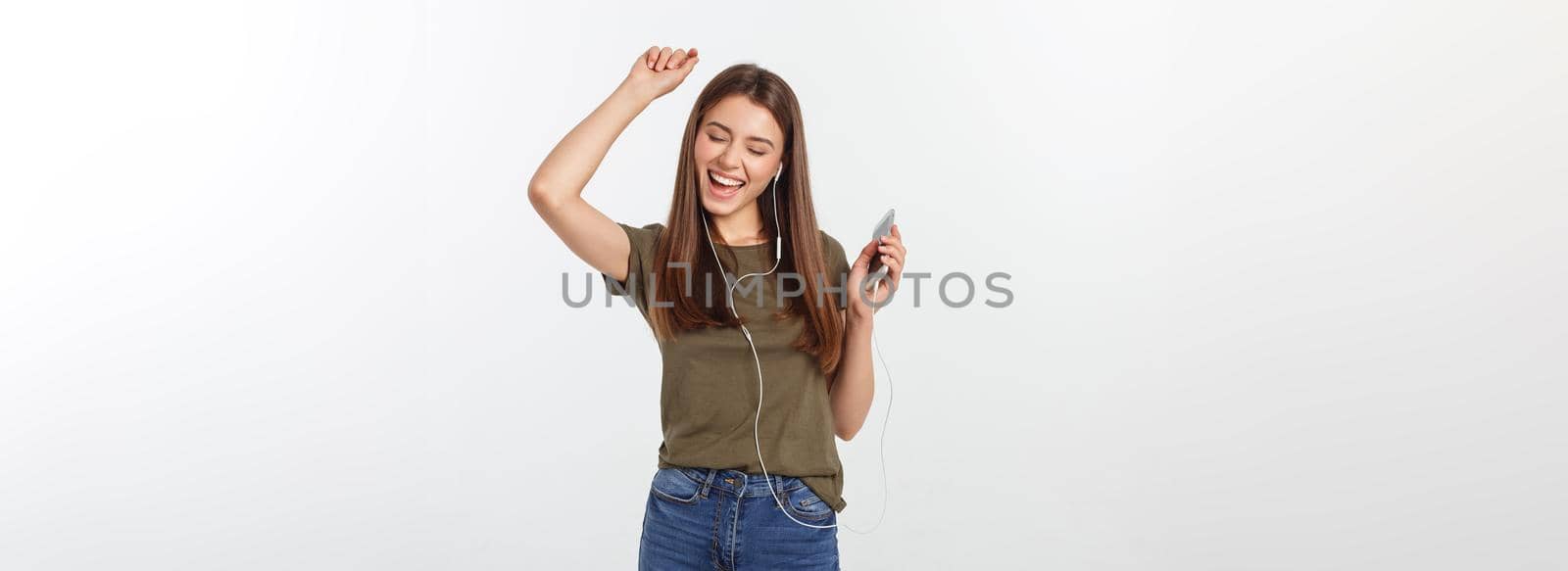 Portrait of a cheerful cute woman listening music in headphones and dancing isolated on a white background. by Benzoix