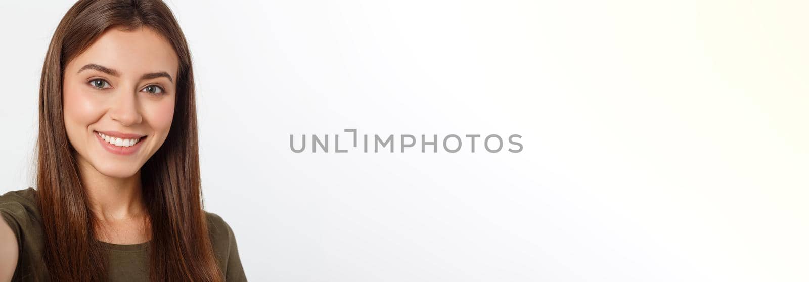 Portrait of a smiling cute woman making selfie photo on smartphone isolated on a white background. by Benzoix