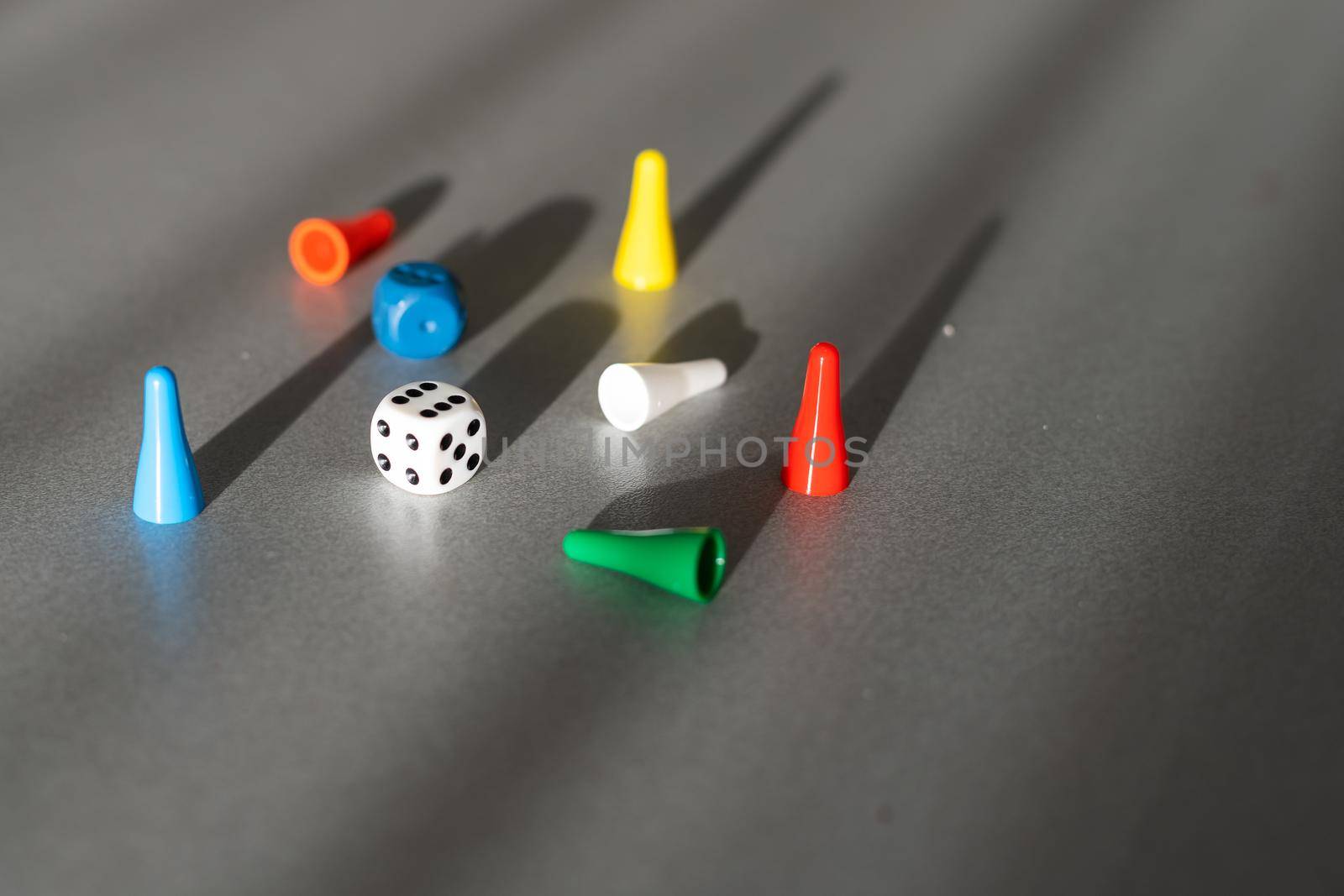 Colorful game chips and two dice are laid out on a gray background: entertainment, games at home for the whole family, the concept of Board games. Board game. Table games, space for text.