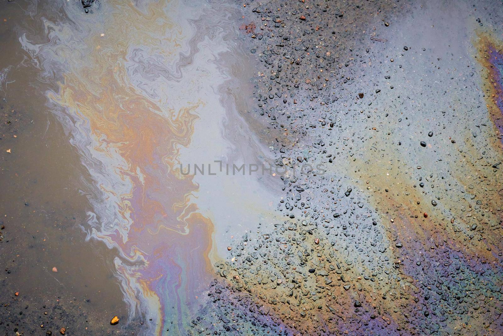 Oil stain on the asphalt, rainbow-shaped colored gasoline stains on an asphalt road as a texture or background
