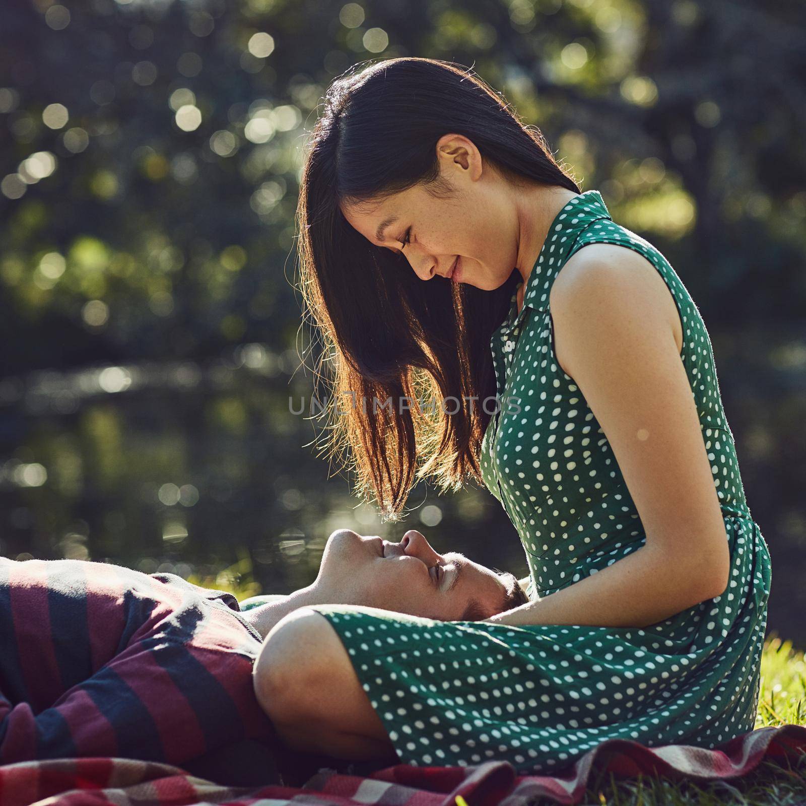 The perfect spot for some romance. an affectionate young couple relaxing together on a picnic blanket in the park