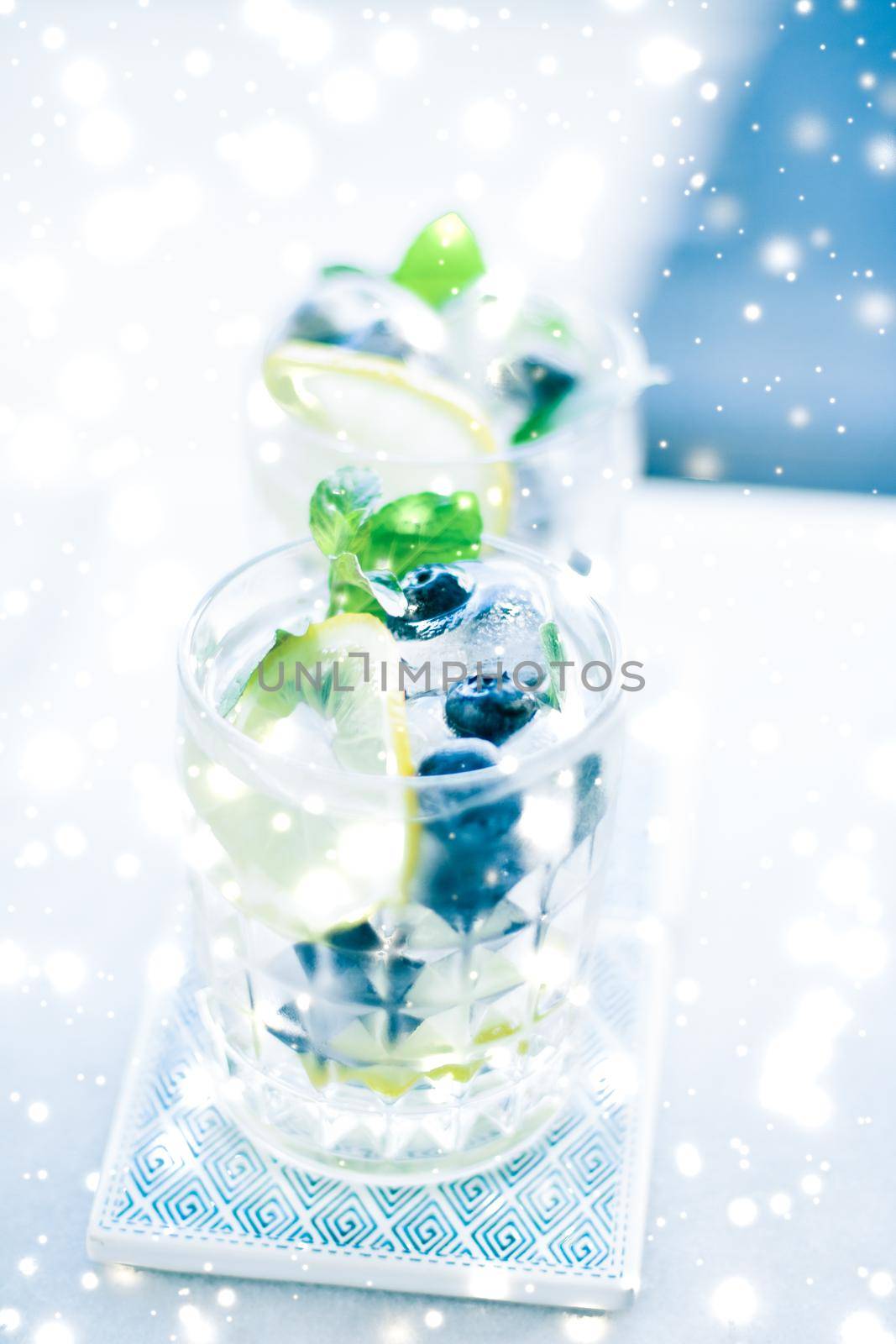 Winter holiday cocktail with ice and glowing snow on background, Christmas time menu recipe by Anneleven