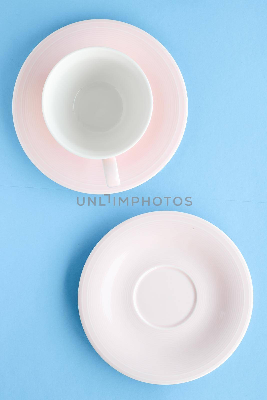 Empty cup and saucer on blue background, flatlay by Anneleven