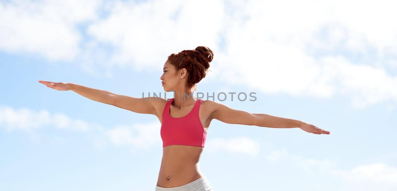Striving to perfect her pranayama. a young woman practicing yoga outside on a sunny day