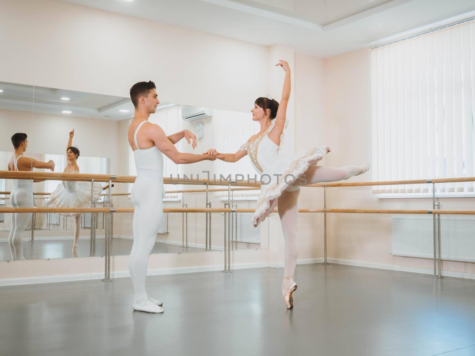 Professional, emotional ballet dancers practicing in the gym or hall with minimalism interior. Couple dancing a sensual dance before performance.