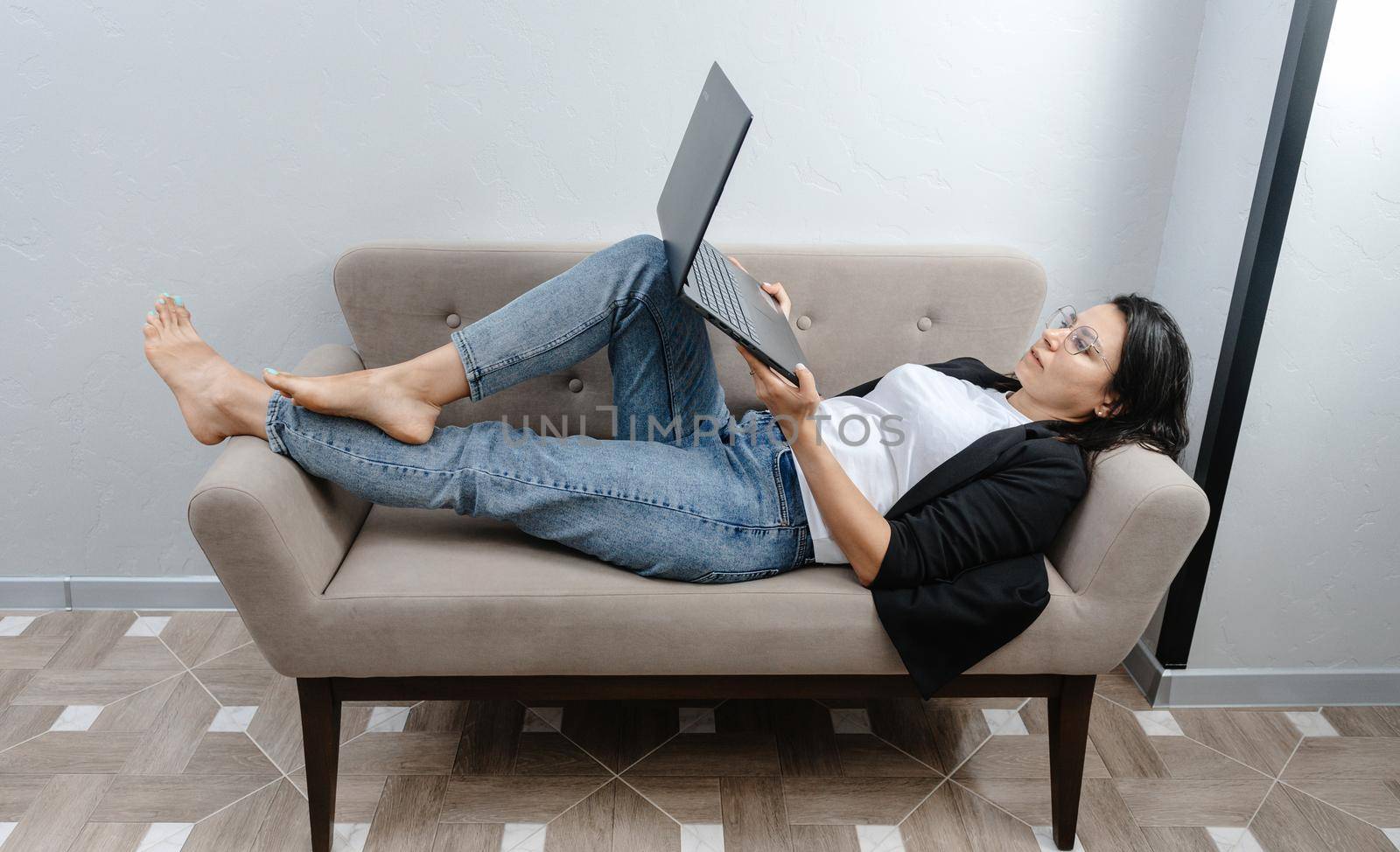 Happy calm female employee working at her laptop in the comfort of her couch. Work at home. Comfortable working at the computer. by gulyaevstudio