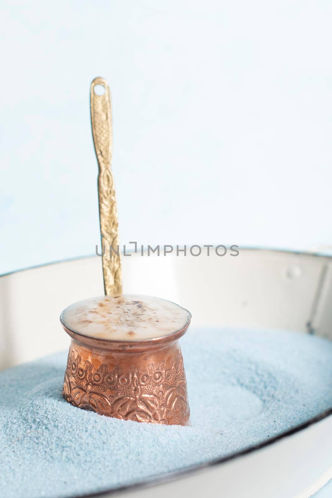 copper coffee pot with hot coffee on blue sand and blue background, beautiful blue color, coffee break, turkish coffee. High quality photo