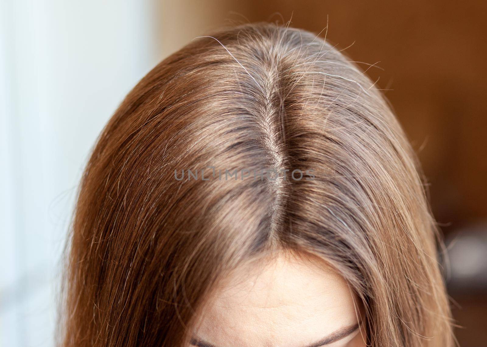 Parting of women's hair on the head. Hair care and care. Closeup of a woman's head with parted gray hair regrown roots becouse of quarantine