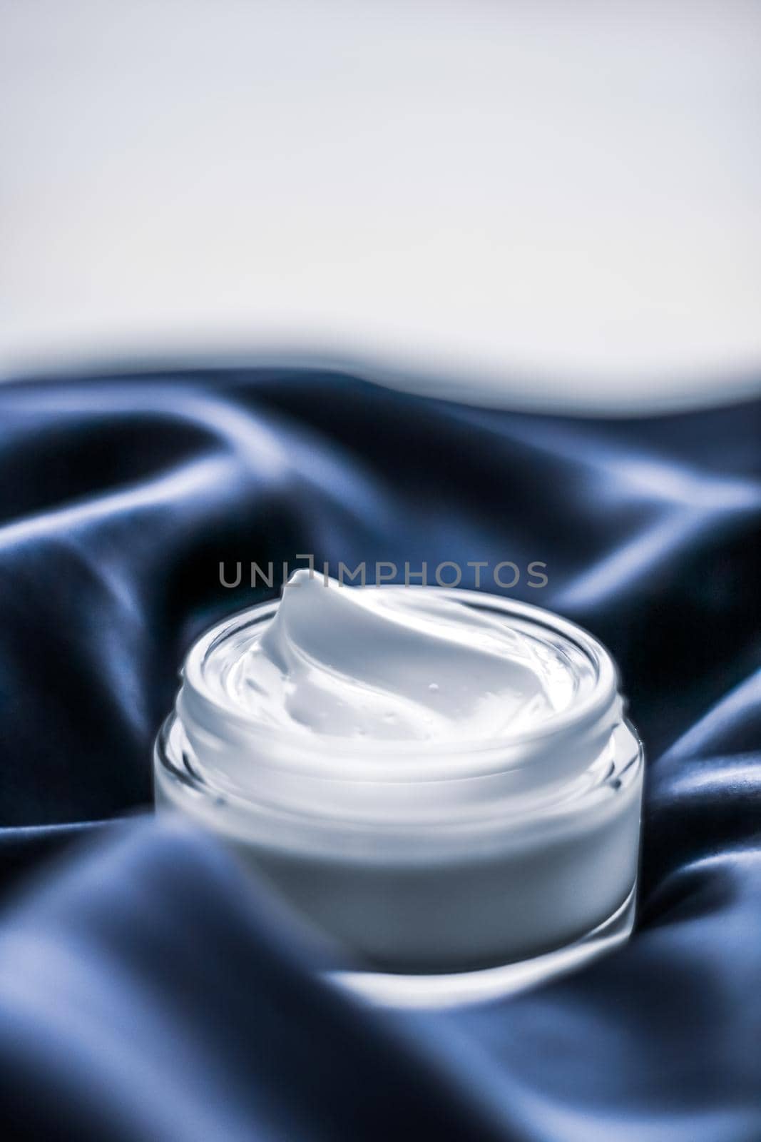 Luxury face cream jar on a dark blue silk by Anneleven