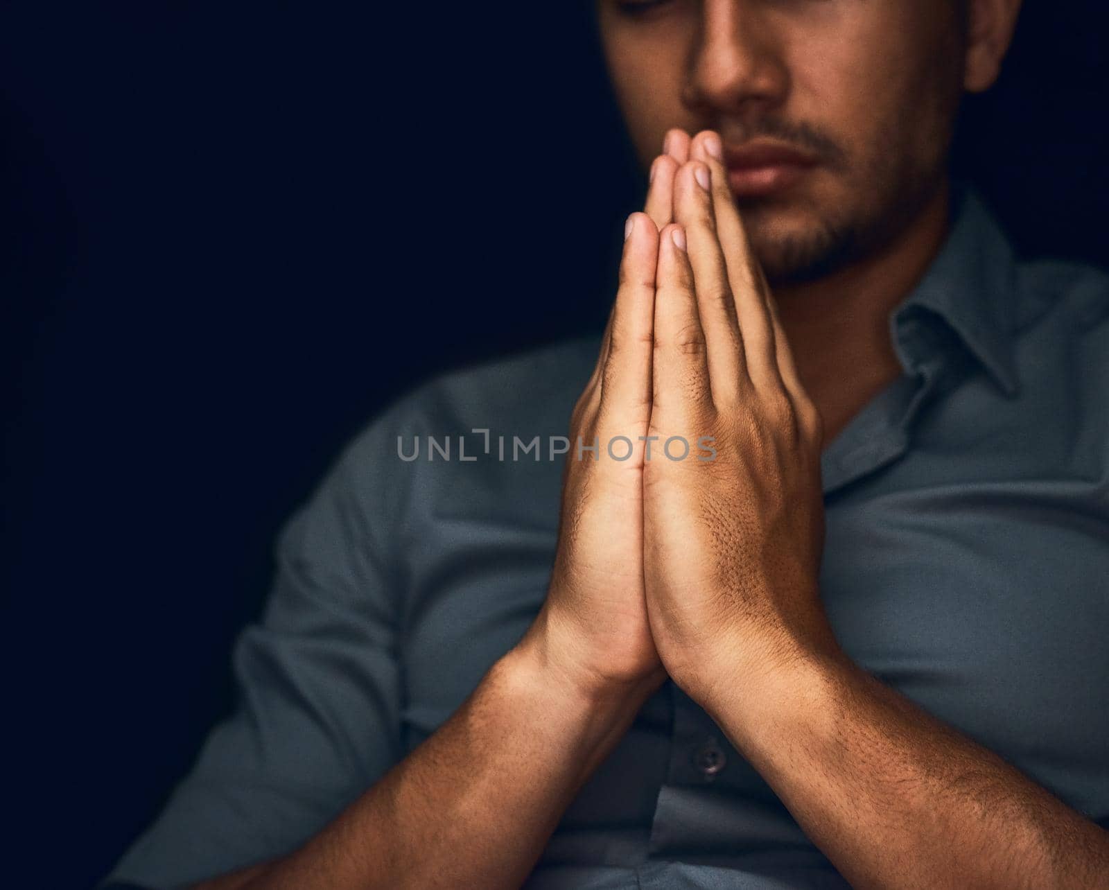Give us this day our daily bread. Closeup shot of a young man praying with his eyes closed. by YuriArcurs