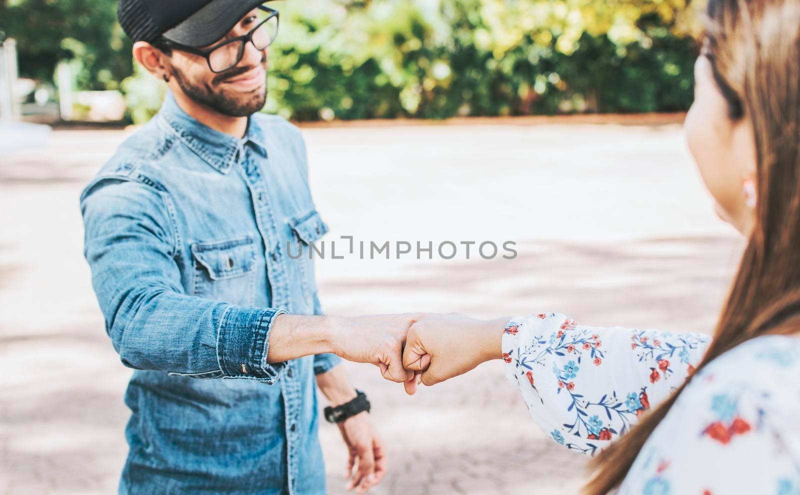Close up of guy and girl shaking fists in the street. A guy and girl shaking hands on the street. Two young smiling teenagers shaking hands in the street by isaiphoto