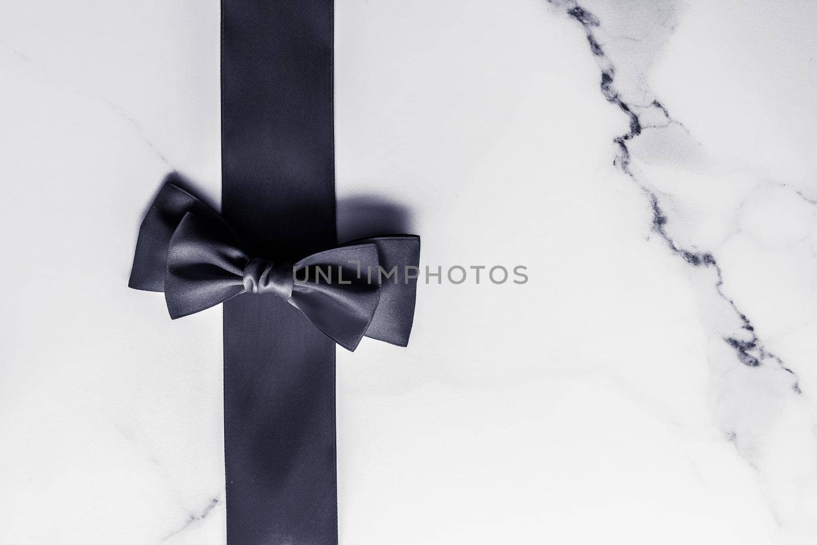 Holiday gift, decoration and sale promotion concept - Black silk ribbon and bow on marble background, flatlay