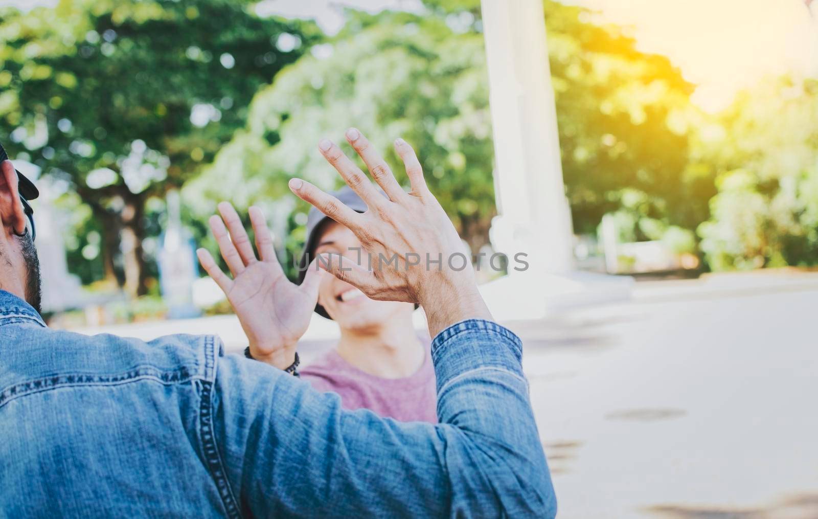 Close up of smiling people shaking hands in a park. Concept of two friends greeting each other with a handshake on the street, Back view of two smiling friends shaking hands on the street