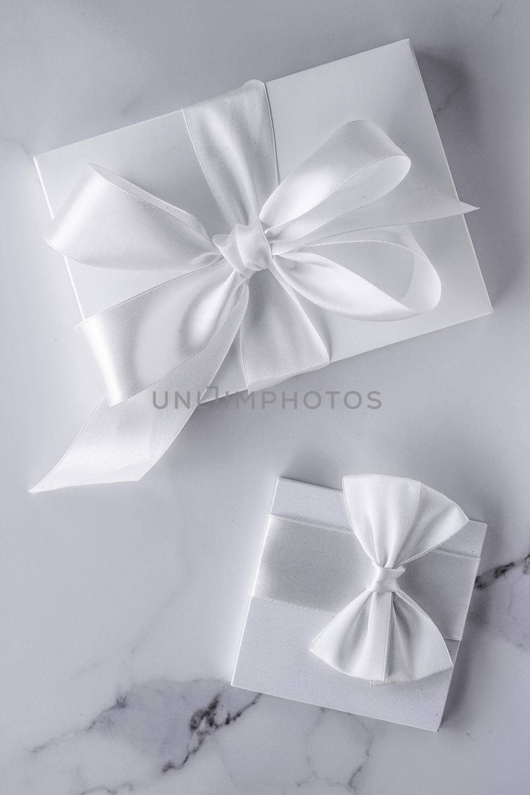 Luxury wedding gifts with silk bow and ribbons on marble background by Anneleven