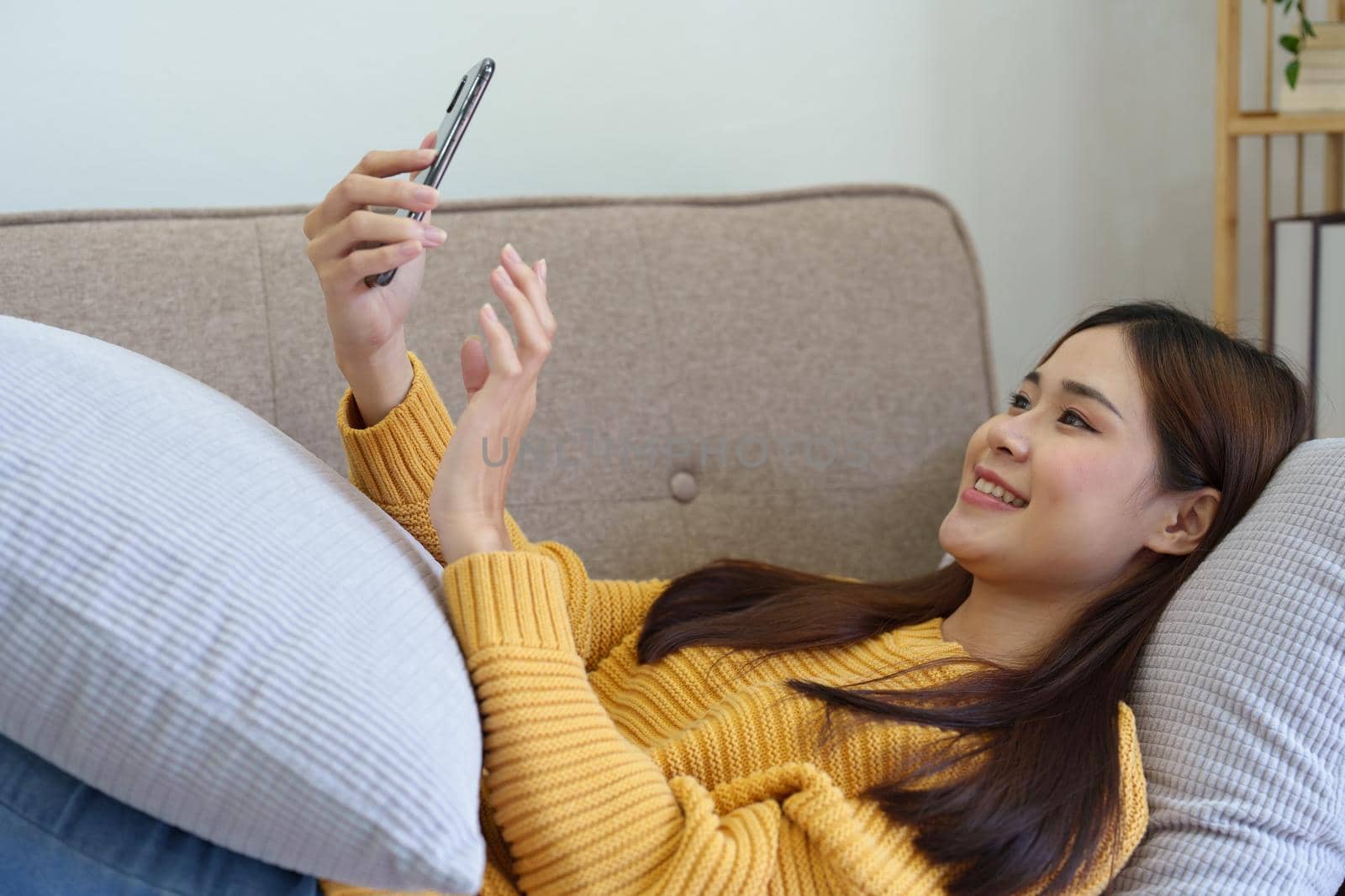 woman sleeping on sofa at home ready to use mobile phone by Manastrong