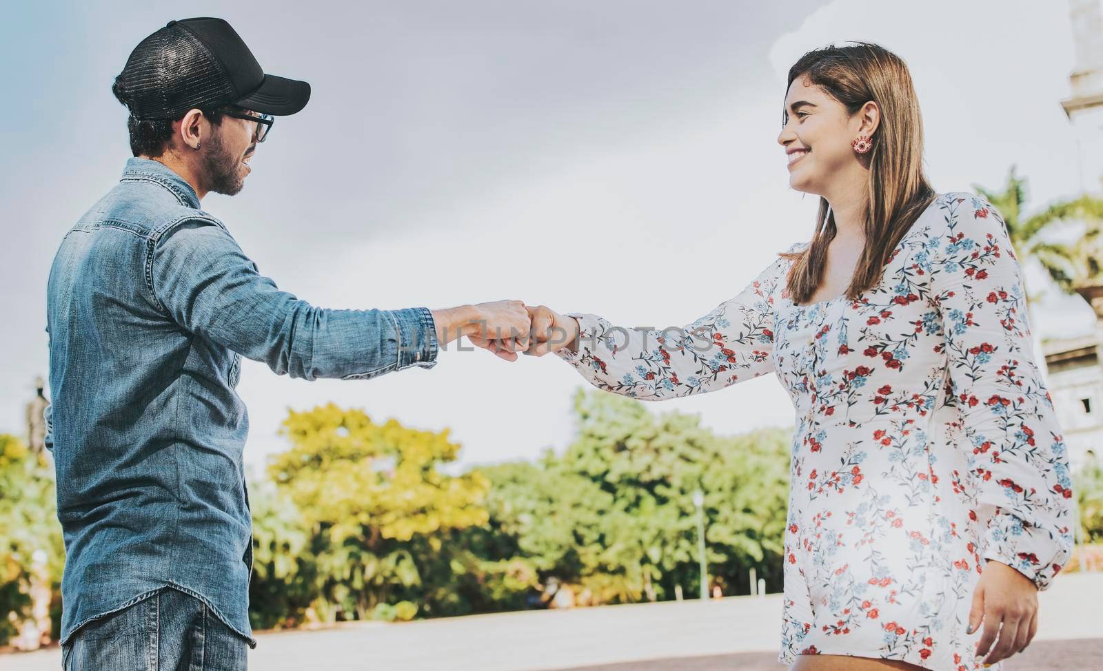 A guy and girl shaking hands on the street. Two young smiling teenagers shaking hands in the street. Concept of man and woman shaking hands on the street.