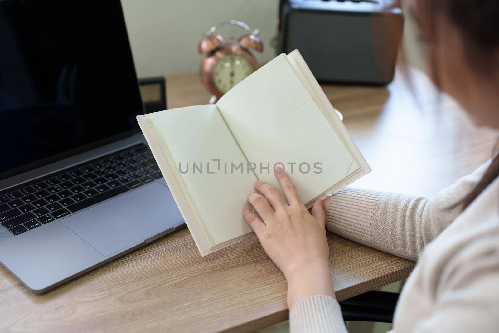 woman sitting at home reading a notebook and using a computer by Manastrong