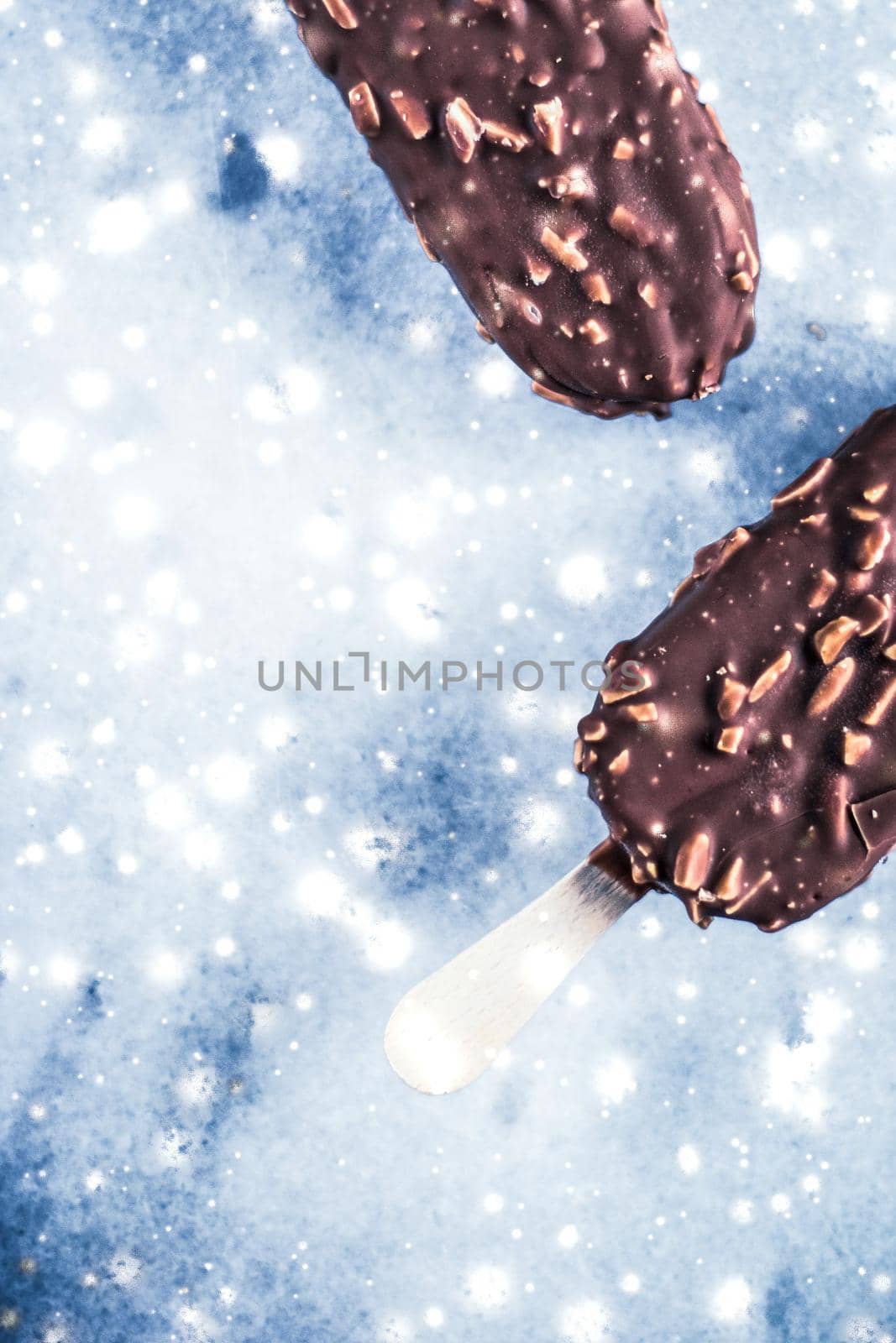 Chocolate almond ice cream on marble table with glowing snow, winter holiday food background by Anneleven