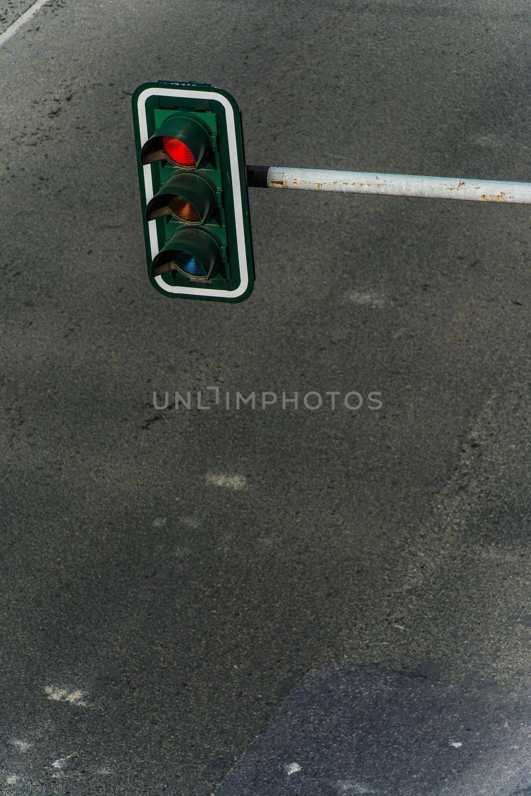 High angle day view of overhead hanging traffic light on a pole above an empty asphalt road.