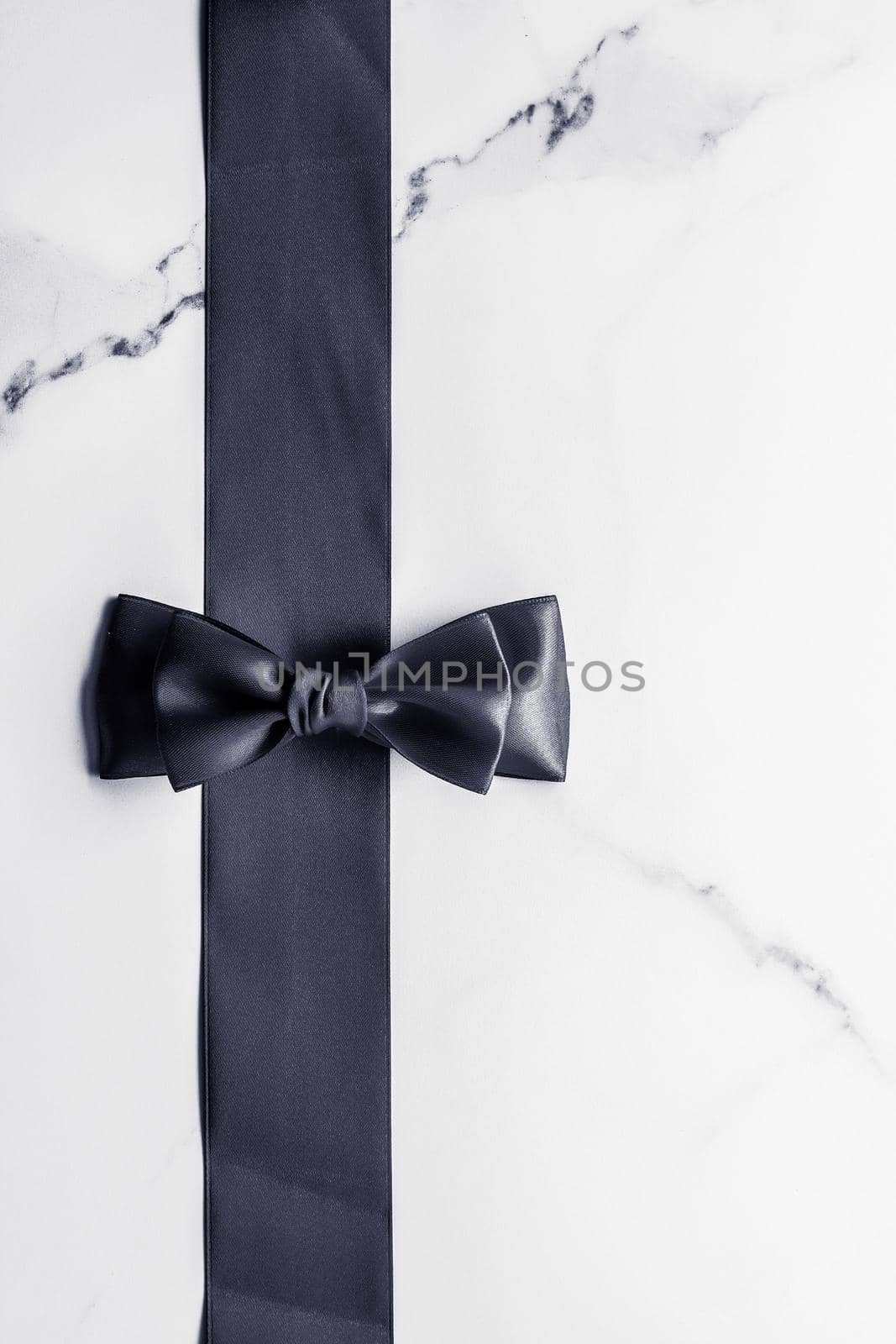 Holiday gift, decoration and sale promotion concept - Black silk ribbon and bow on marble background, flatlay