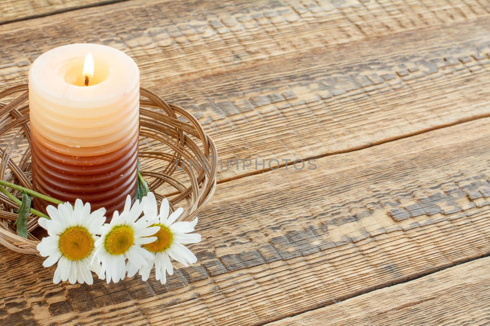 Burning candle and fresh flowers on wooden table. by mvg6894