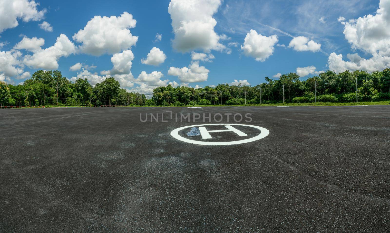 Asphalt helipad in the forest. Landscape of helipad. Helipad area against blue sky and white cumulus clouds in sunny day. Platform for helicopters and powered lift aircraft. Heliport of helicopter. by Fahroni