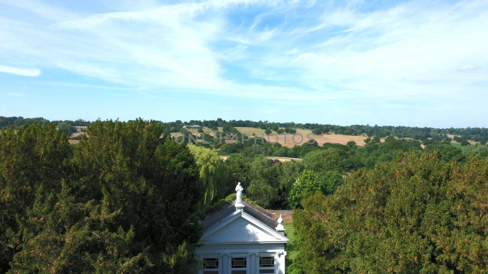 Aerial top down view from the drone onto the narrow passageway leading to a small chapel. Chapel located in a big green open area of fields near Rosary Manor, Mill Hill, North West London, London, UK.