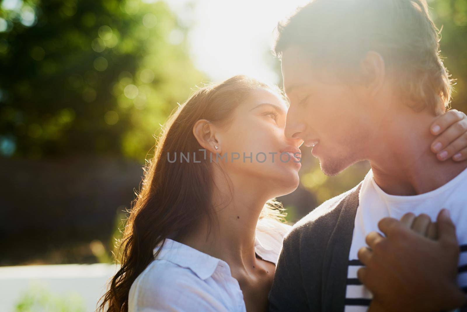You are my only sunshine. an affectionate young couple bonding outdoors. by YuriArcurs
