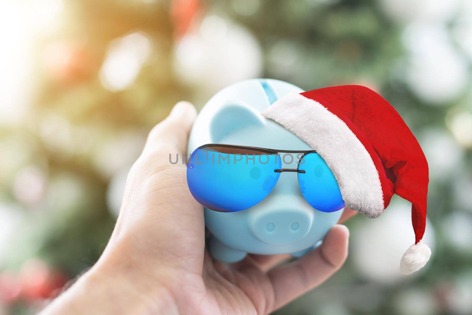 Piggy bank with Santa hat on table against blurred Christmas lights. Space for text