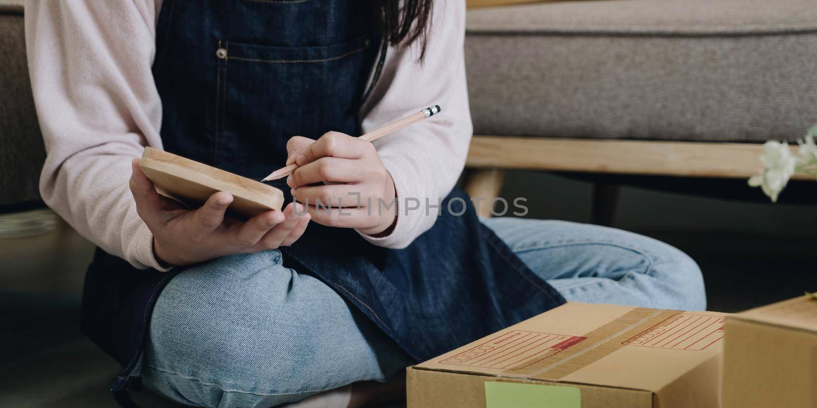 Startup Entrepreneurship Small Business SME Freelance Young lady working at home with boxes on the floor and laptop online Marketing Packaging SME Shipping Ecommerce Concepts by wichayada