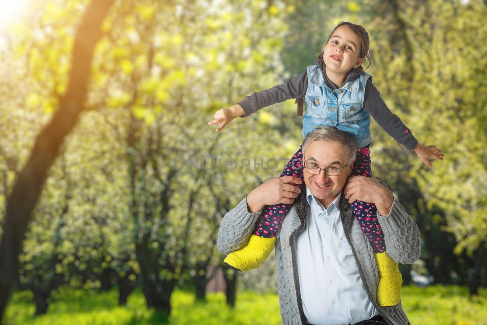 Authentic photo of smiling grandfather hugging with his granddaughter.