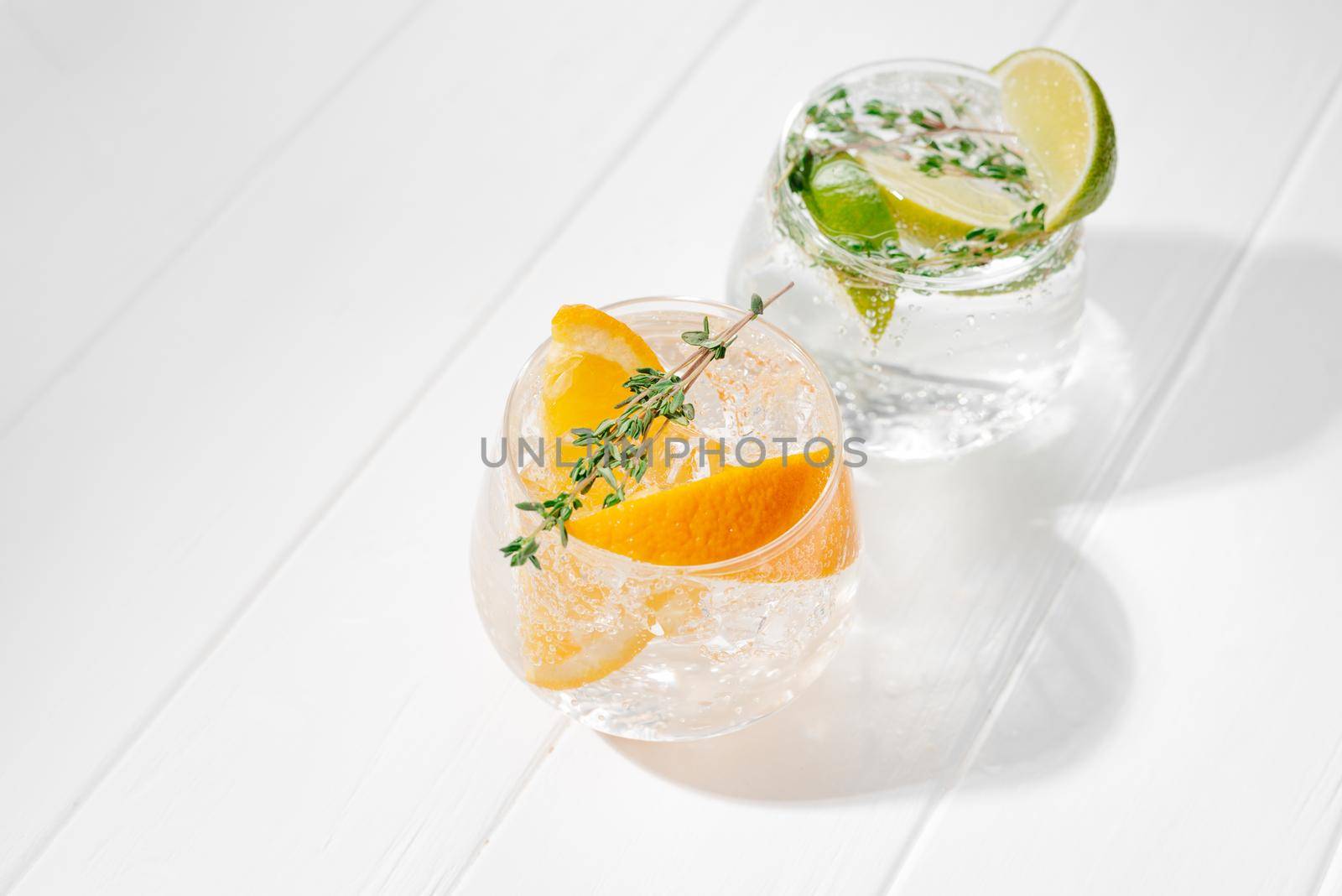 Set of different citrus lemonades with orange and lime on a light background. Tough sunshine. Flashy food.