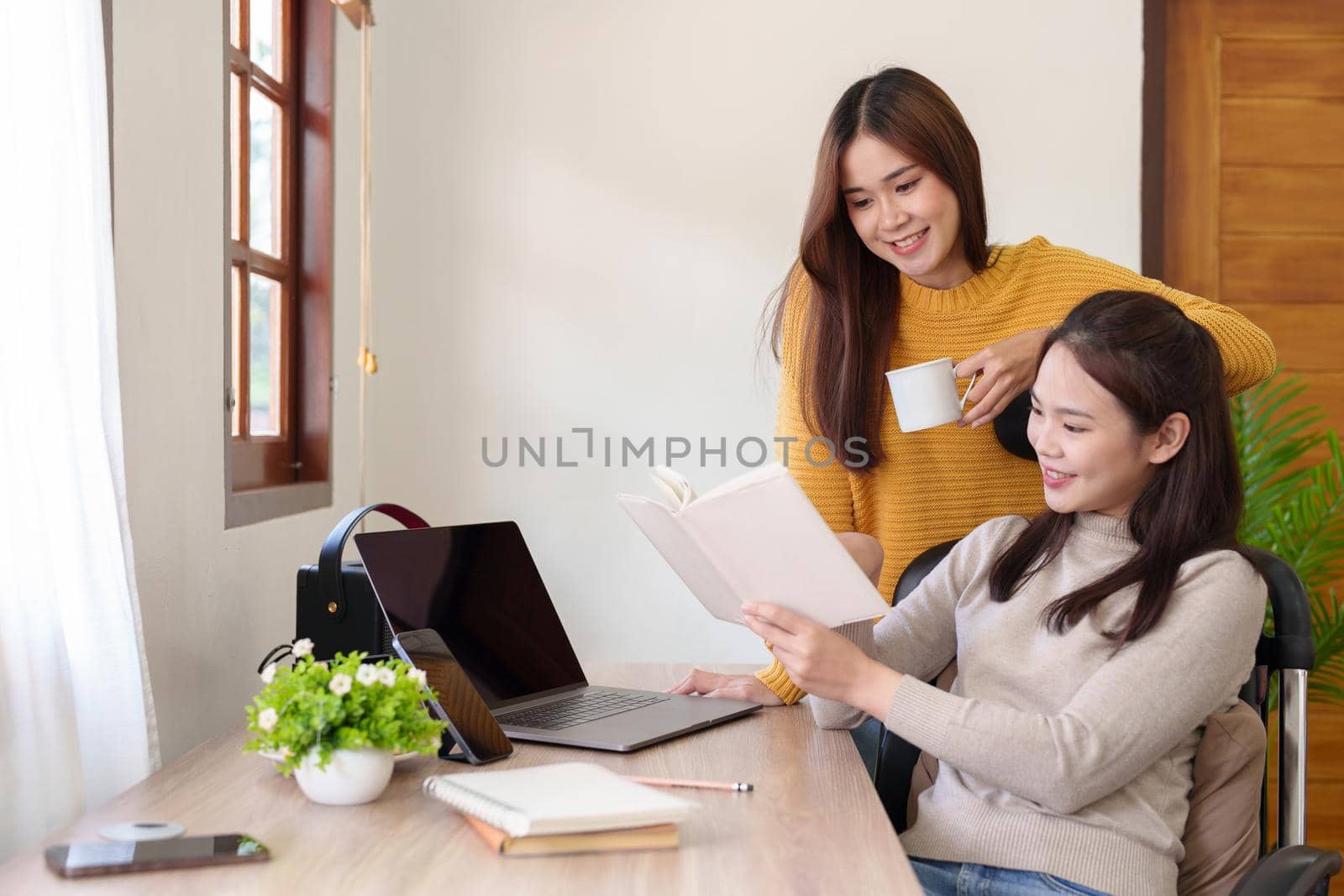 Portrait of two young Asian women discussing while working together in the office.