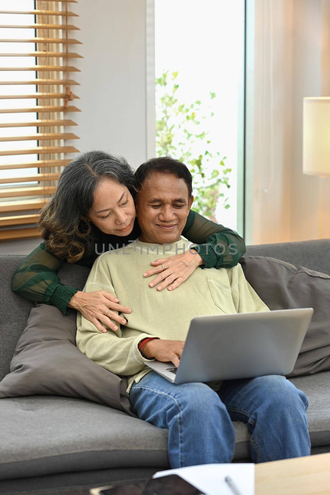 Happy retried couple enjoying spending time together at home and using laptop. Retirement and happy senior lifestyle concept by prathanchorruangsak