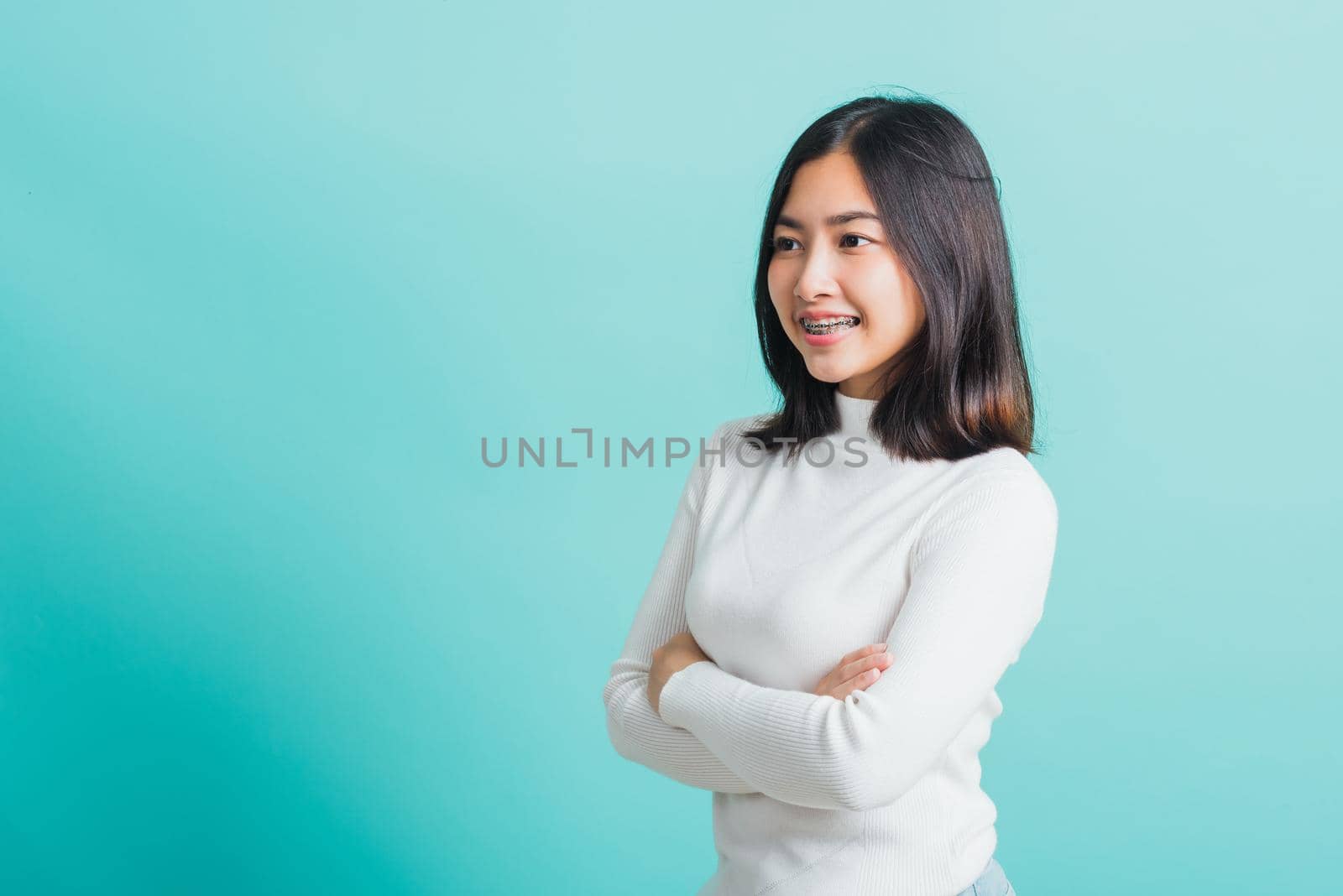 Young beautiful Asian woman smiling with crossed arms, Portrait of positive confident female stand cross one's arm, studio shot isolated on a blue background
