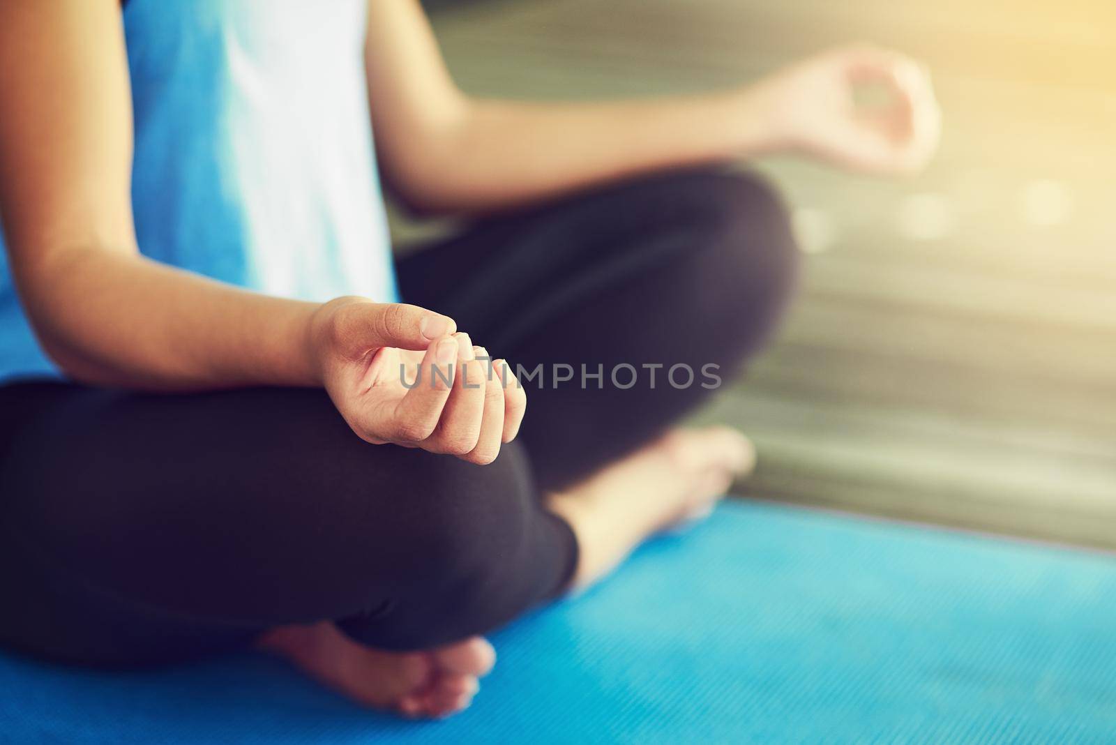 Drop down and give me zen. a young woman sitting in lotus position. by YuriArcurs