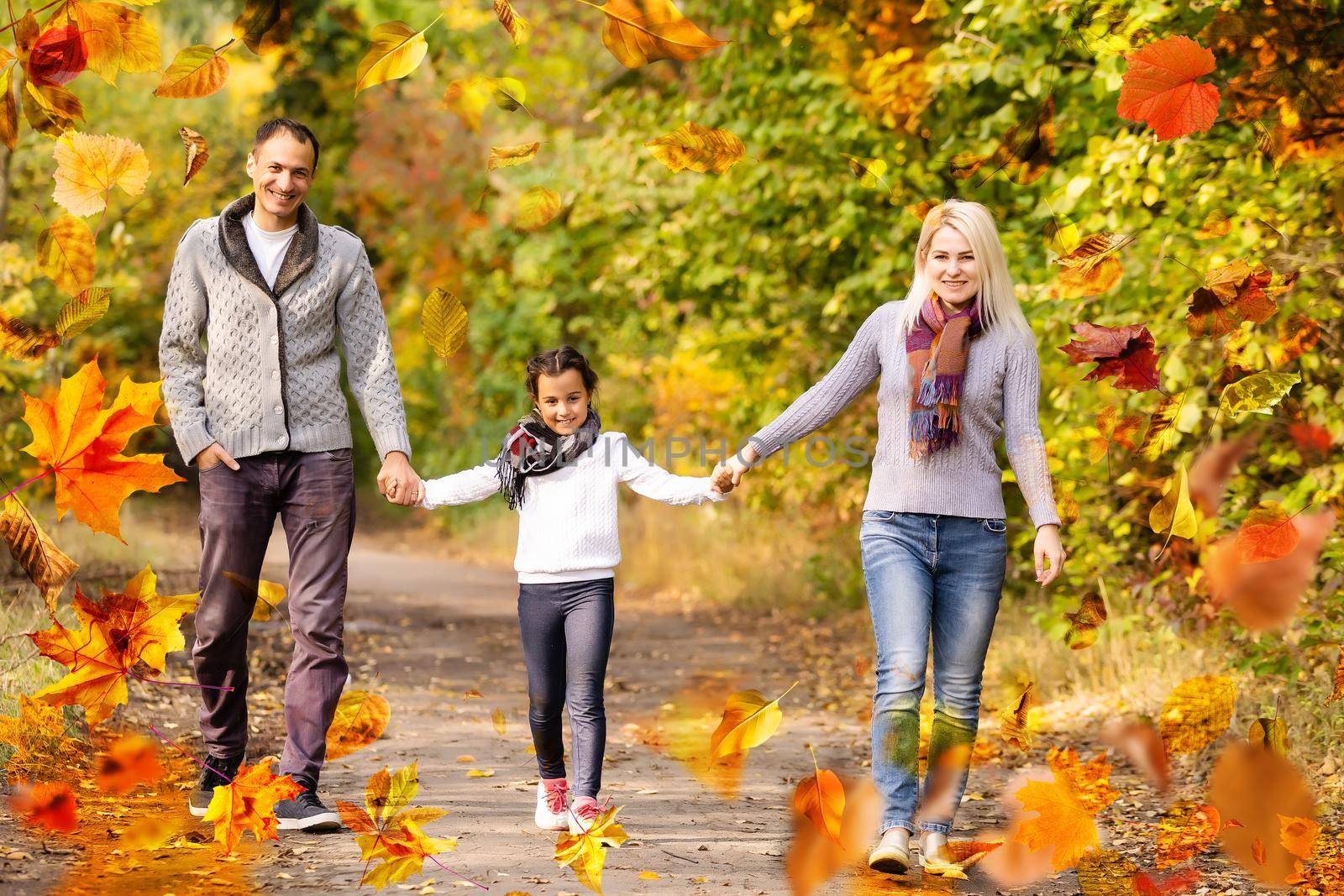 family walking in an autumn park with fallen fall leaves by Andelov13