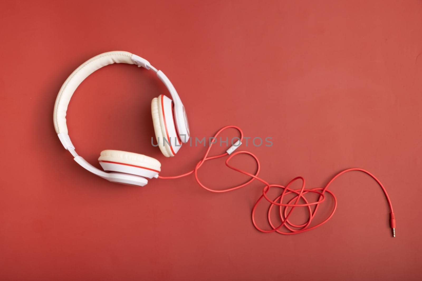 White-colored headphones on red background. Minimalistic fashion music concept. Top view, flat lay.