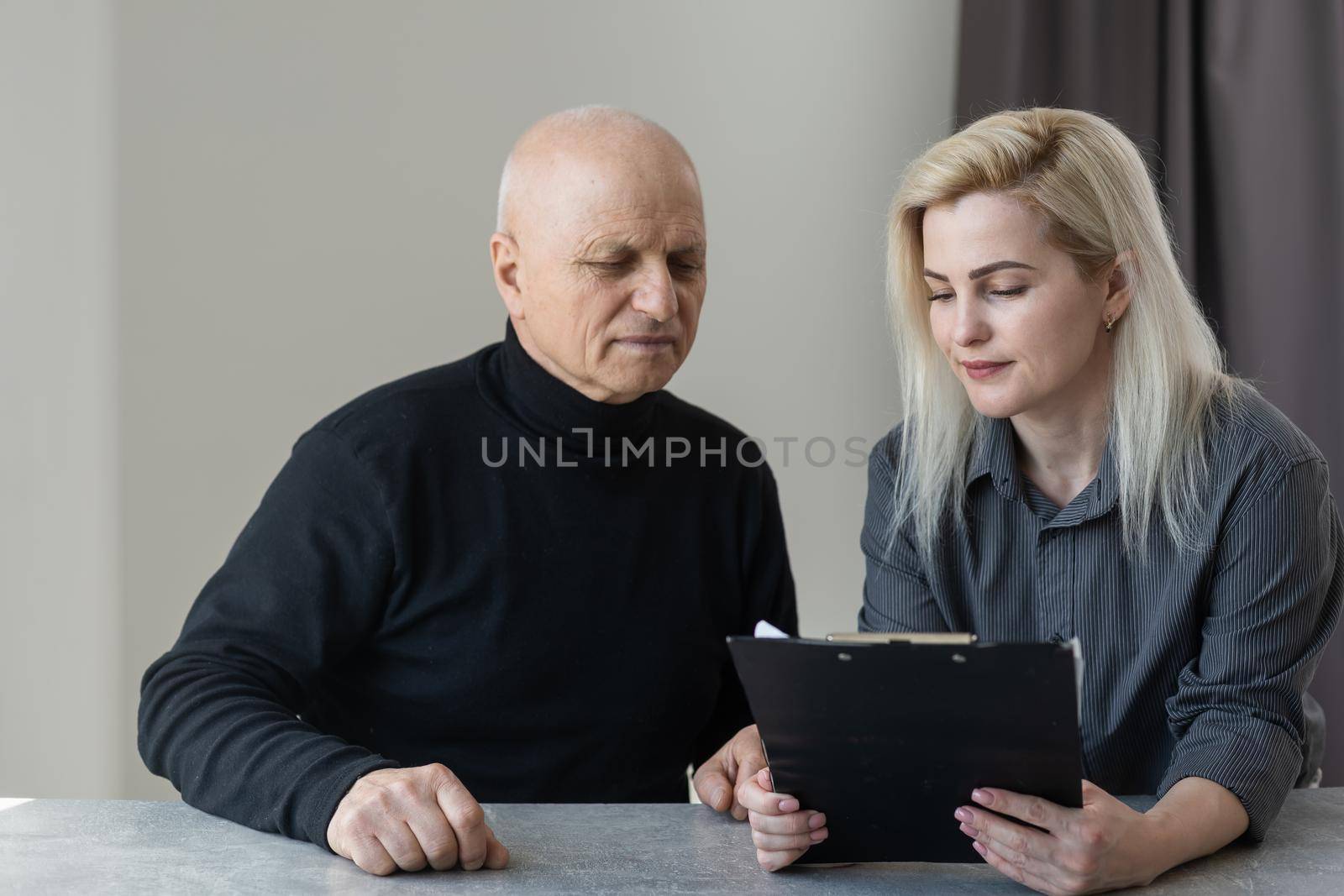 Close up of smiling young Caucasian female therapist or GP have consultation with old male patient in clinic or hospital. Happy woman doctor talk consult elderly man client. Healthcare concept.